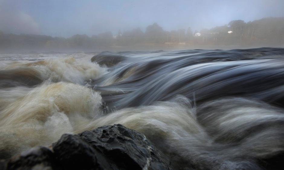 Swollen from recent rains, the Penobscot River flows through the area of the river where the Veazie Dam once stood. The dam, along with the Great Works Dam farther downstream, was removed two years ago in an effort to allow salmon easier passage to spawning grounds upriver from the dam. Photo: Gregory Rec, Staff Photographer