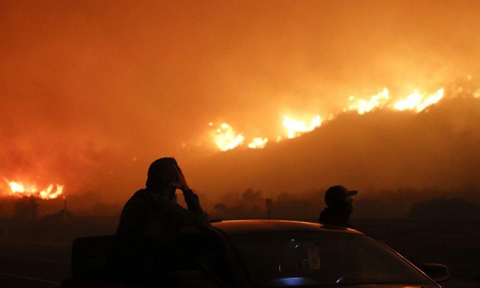 Two spectators watch as a wildfire burns along the 101 Freeway Tuesday, Dec. 5, 2017, in California. Photo: Jae C. Hong, AP