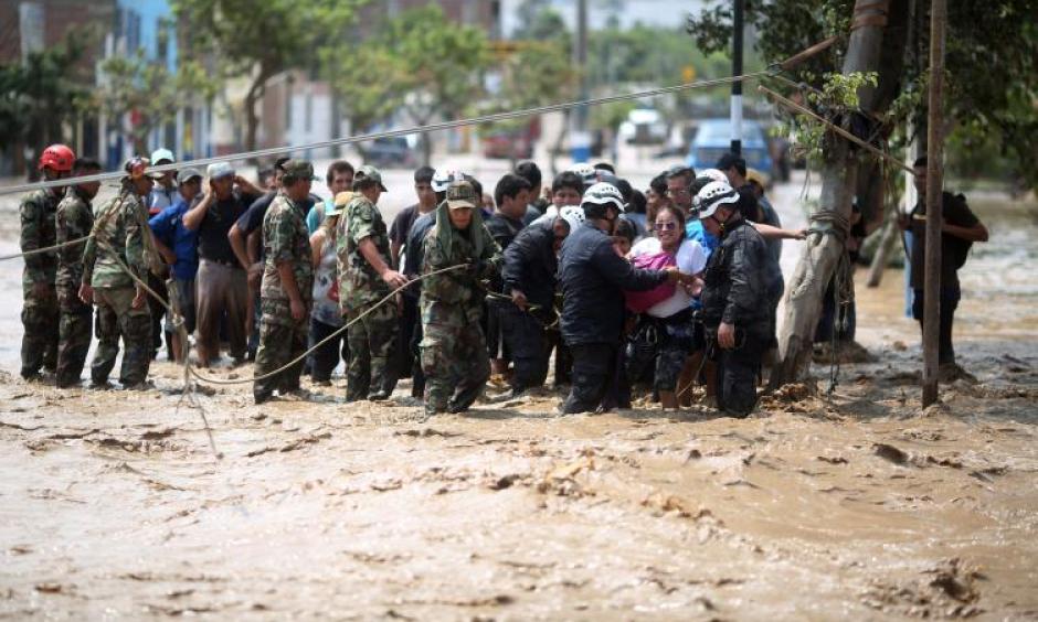 Police help residents cross a flooded street after a massive landslide and flood in the Huachipa district of Lima, Peru, March 17, 2017. Photo: Sebastian Castaneda, Reuters