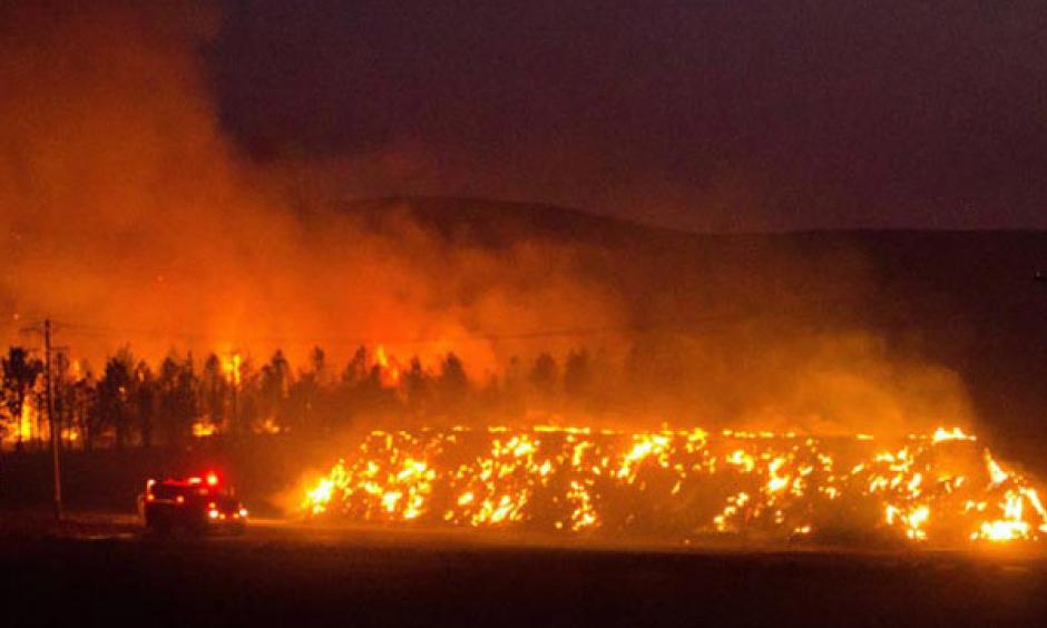 A fire truck moves along Hwy 125 past a blazing stack of hay bales north of Walla Walla during a large wildfire Aug. 21, 2016. The fire, whose cause is under investigation, burned about 15,000 acres. Photo: Greg Lehman / Walla Walla Union-Bulletin via AP