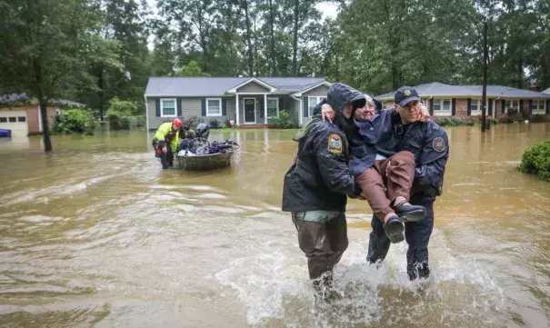 Department of Natural Resources officer Brett Irvin and Lexington County deputy Dan Rusinyak carry June Loch to dry land after she was rescued from her home in Columbia, South Carolina. Credit: Tim Dominick, Rex Shutterstock