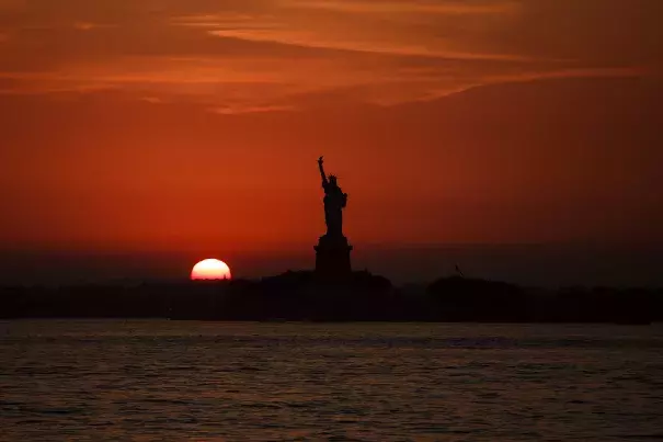 In this July 1, 2018 file photo, the sun sets behind the Statue of Liberty in New York as record high temperatures were recorded over the week in the U.S. and elsewhere. An AP data analysis of records from 1999-2019 shows that in weather stations across America, hot records are being set twice as often as cold ones. Photo: Andres Kudacki, AP
