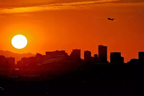 FILE - A jet takes flight from Sky Harbor International Airport as the sun sets over Phoenix, July 12, 2023. The toll of heat associated deaths still being tallied after the hottest summer ever in Arizona’s most populous county has now soared over 360, alarming public health officials. (Credit: AP Photo/Matt York, File)