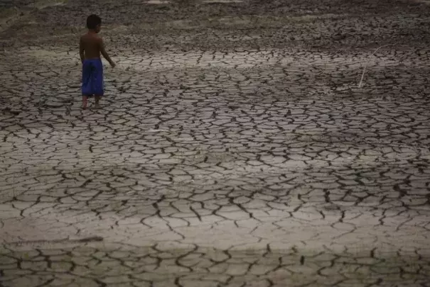 A boy walks on a dry area of the Igarape do Taruma stream which flows into the Rio Negro river, as the water level at a major river port in Brazil's Amazon rainforest hit its lowest point in at least 121 years, in Manaus, Brazil October 16. (Credit: REUTERS/Bruno Kelly)