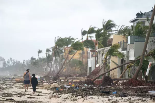 People walk along the beach looking at property damaged by Hurricane Ian on September 29, 2022 in Bonita Springs, Florida. The storm made a U.S. landfall on Cayo Costa, Florida, and brought high winds, storm surges, and rain to the area causing severe damage. (Credit: Sean Rayford/Getty Images)