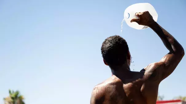 A person cools off amid searing heat that was forecast to reach 115°F in July in Phoenix, Arizona, which became the first major U.S. city to reach an average monthly temperature higher than 100°F over the summer. (Credit: Brandon Bell/Getty Images)
