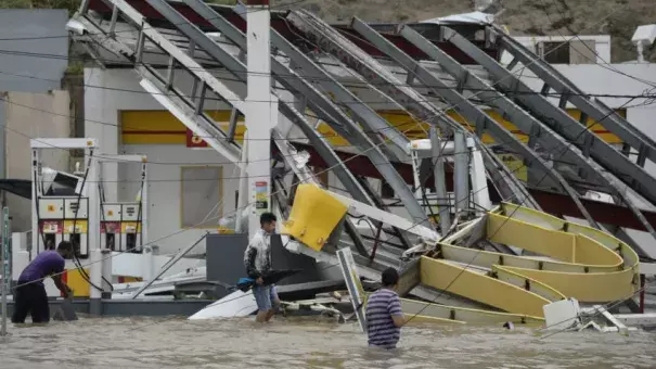 People walk next to a gas station Wednesday flooded and damaged by the impact of Hurricane Maria in Humacao, Puerto Rico. Photo: Carlos Giusti, AP