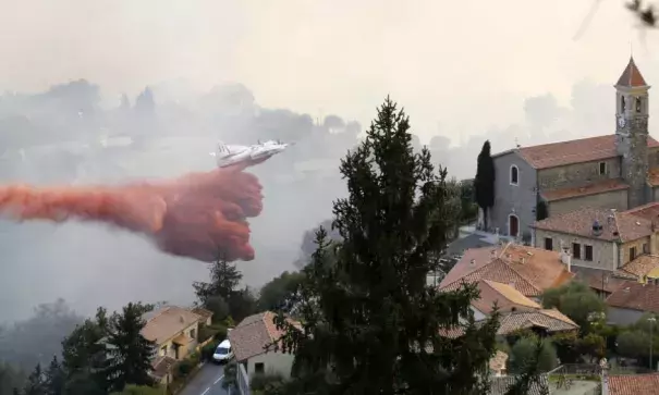 A firefighting aircraft dumps its load on a forest fire in the town of Castagniers near Nice, southern France. Photo: EPA