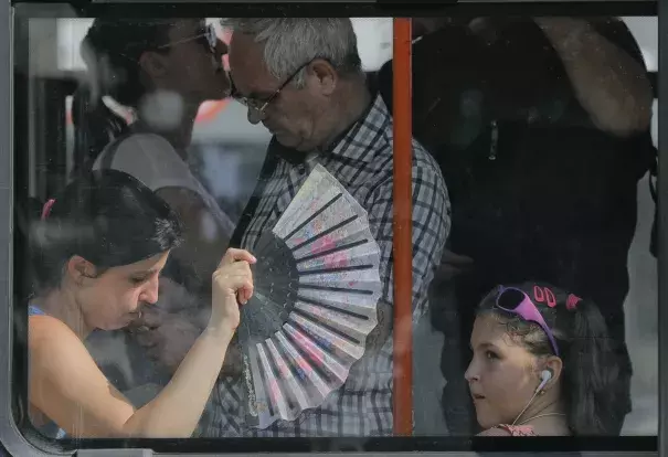 A woman uses a fan to cool herself and a child wile ridding on a tram in Bucharest, Romania, Friday, Aug. 4, 2017. Romanian meteorologists issued an extreme temperatures warning, with 42 Celsius (107.6 F) forecast for parts of western Romania and placing 12 counties under a "red code" heat alert for the next two days. Photo: Vadim Ghirda, AP