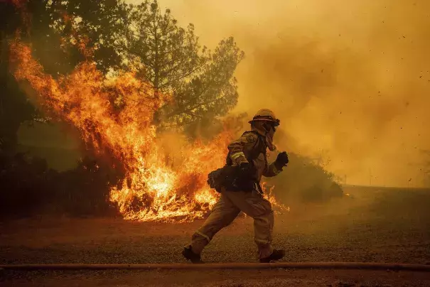 A firefighter runs while trying to save a home as a wildfire tears through Lakeport (Lake County) on Tuesday. The shift in the jet stream that’s driving the West’s stagnant hot weather is almost certainly the result of global warming, climate scientists say. Credit: Noah Berger, Associated Press