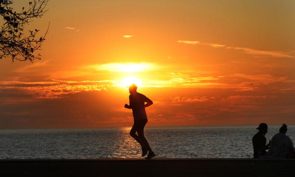 A hot yellow sun rises on Lake Michigan at Montrose Avenue Monday Sept. 25, 2017 as a jogger takes advantage of the cool early morning temperatures. Although still cool at sunrise another record-breaking hot day was expected for the Chicago area. Photo: Nancy Stone / Chicago Tribune