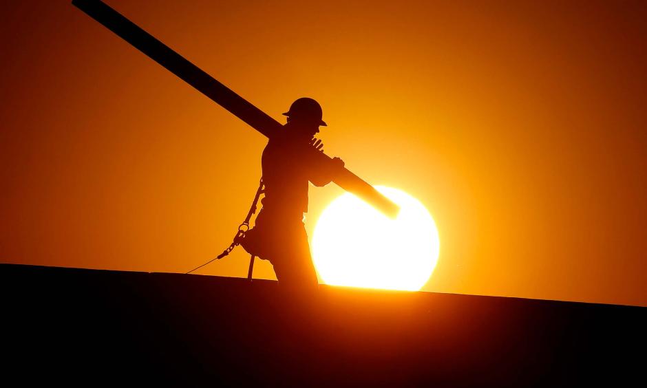 A home builder works at sunrise on Monday, June 20, in Gilbert, Arizona, in an effort to beat the rising temperatures. Photo: Matt York / AP