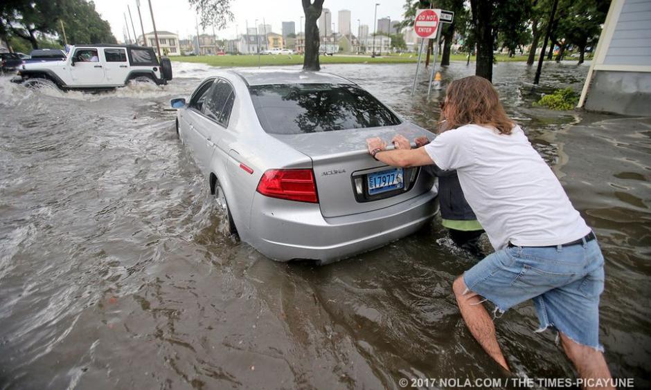 Good Samaritans push a flooded car with a family from the waters in the 2000 block of Orleans Avenue as an afternoon deluge flooded the streets of New Orleans on Saturday, July 22, 2017. Photo: Michael DeMocker, NOLA.com, The Times-Picayune