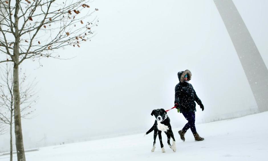 Patti White walked her dog Elwood around the Gateway Arch in St. Louis on Sunday. Blowing snow snarled travel across Kansas and Missouri as a winter storm made its way eastward. Credit: Colter Peterson, St. Louis Post-Dispatch, via Associated Press