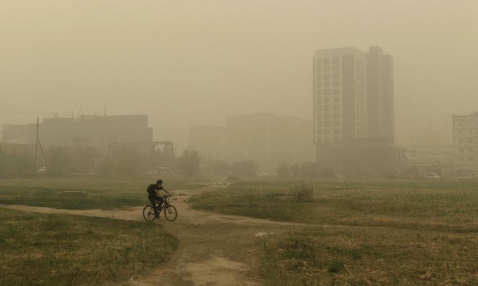 A man rides his bicycle through smoke from a forest fire covers Yakutsk, the capital of the republic of Sakha also known as Yakutia, Russia Far East, Russia, Thursday, Aug. 12, 2021. The U.N. weather agency has certified a 38-degree Celsius (100.4 Fahrenheit) reading in the Russian town of Verkhoyansk last year as the highest temperature ever recorded in the Arctic. The World Meteorological Organization said the temperature "more befitting the Mediterranean than the Arctic" was recorded in June 2020 during