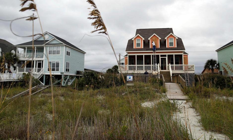 Workers install window shutters at an oceanfront home in anticipation of Hurricane Matthew in Garden City Beach, S.C., U.S. Oct. 5, 2016. Photo: Randall Hill