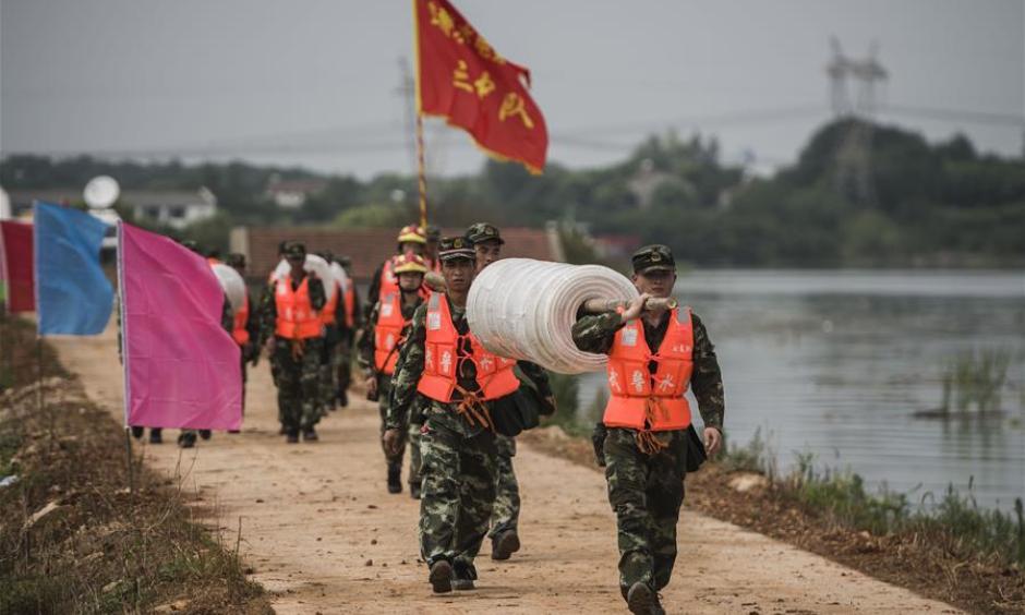 Armed police soldiers prepare for the breach of the embankment on the dike of Niushan Lake in central China's Hubei Province, July 13, 2016. The Hubei provincial government Tuesday decided to break the embankment between Liangzi Lake and Niushan Lake, to prevent possible flood overflow over the dike. The operation will be executed on July 14. Photo: Xiao Yijiu, Xinhua