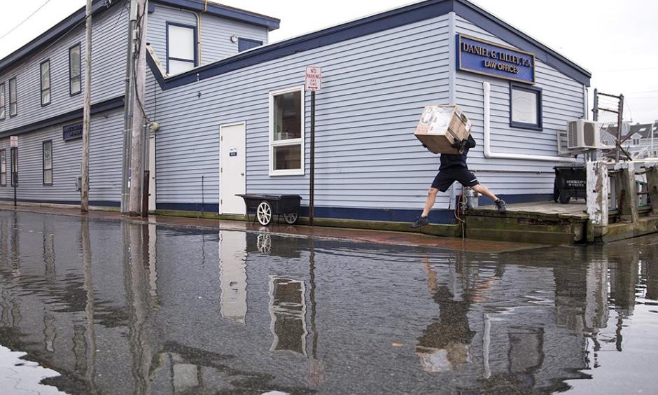 A FedEx delivery man jumps over pooling water on Portland Pier during the king tide. Tides are caused by the gravitational pull of the moon and this week's supermoon was closer to Earth than it has been in 68 years. Photo: Brianna Soukup