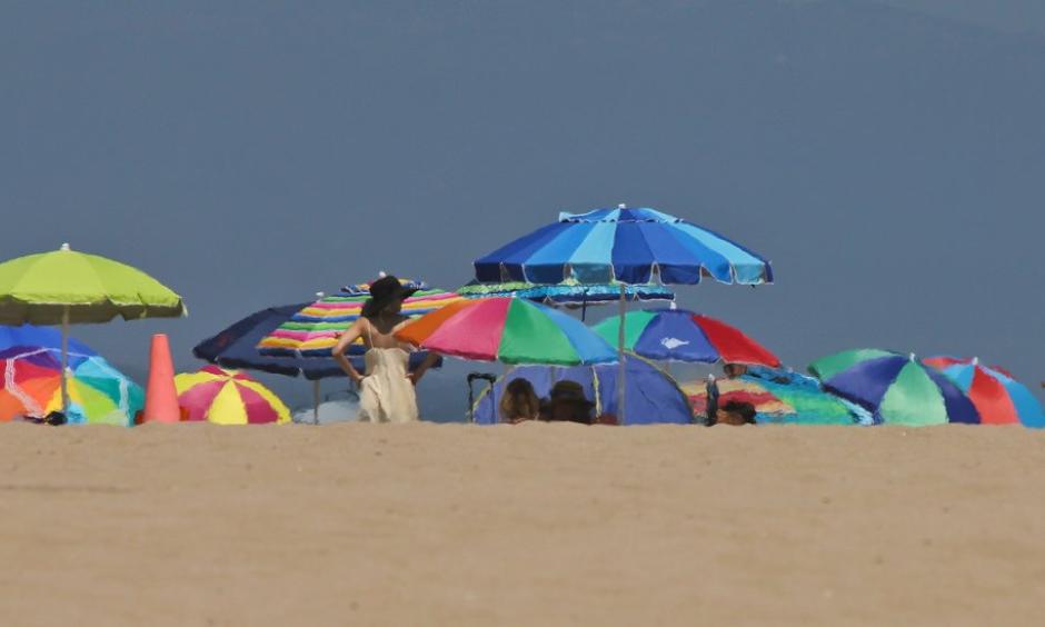 Beachgoers camped out under umbrellas at Manhattan beach this summer. A heat wave is expected to push Southern California temperatures into the triple digits. Photo: John Antczak, Associated Press
