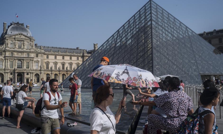 People cool off next to the fountains at Louvre Museum in Paris, France, Wednesday, July 24, 2019. Temperatures in Paris are forecast to reach 41 degrees C (86 F), on Thursday. Credit: Rafael Yaghobzadeh, AP