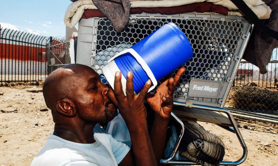 Desmont Smith sits in the shade of his shopping cart drinking water in Phoenix. Credit: Ann Johansson, Corbis via Getty Images