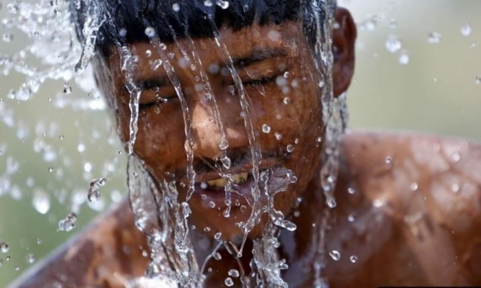 A worker takes a bath from the water of a bore pump on a hot summer day during a heat wave in Gurgao, India, on May 29, 2015. Photo: Anindito Mukherjee, Reuters