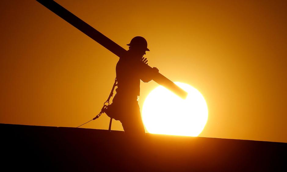 A home builder works at sunrise on Monday in Gilbert, Arizona, in an effort to beat the rising temperatures. Photo: AP