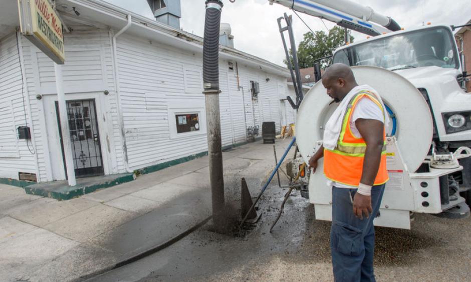 A New Orleans city worker sprays out mud and debris from a storm drain at Wille Mae's Restaurant before the governor toured it and other businesses damaged by Saturday's flash flooding in New Orleans, La. Monday, Aug. 7, 2017. Photo: Matthew Hinton