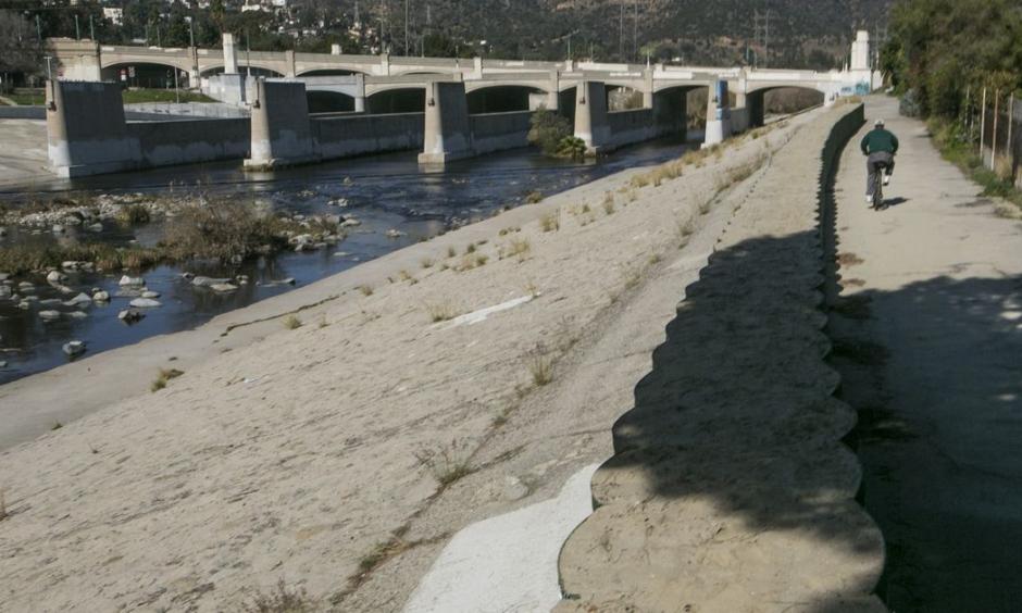 A cyclist rides along recently installed temporary flood control walls along the L.A. River in Los Angeles Friday, Feb. 12, 2016. Ten days with record heat and no rain have Californians worrying about the drought again. Photo: Damian Dovarganes, AP