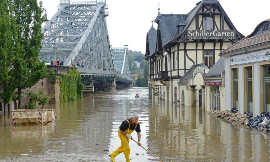 A helper cleans the bank of river Elbe in front of the historical bridge Blaues Wunder (Blue Miracle), left, in Dresden, eastern Germany, Thursday, June 6, 2013. Photo: Jens Meyer, AP