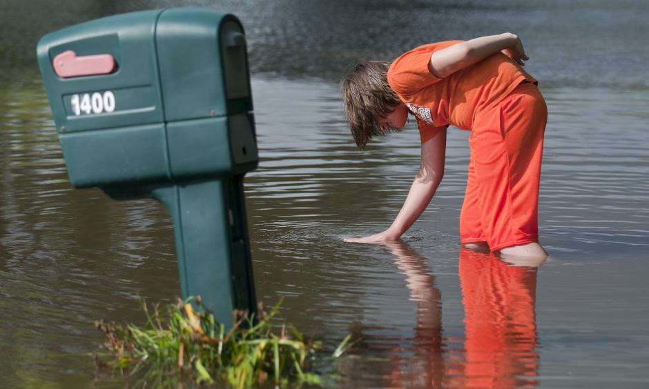 Logan Krevchuck, 14, puts his hand in a whirlpool as flood waters drained along Second Street Northwest in Waseca, Minn., Thursday. Photo: Jackson Forderer for MPR News