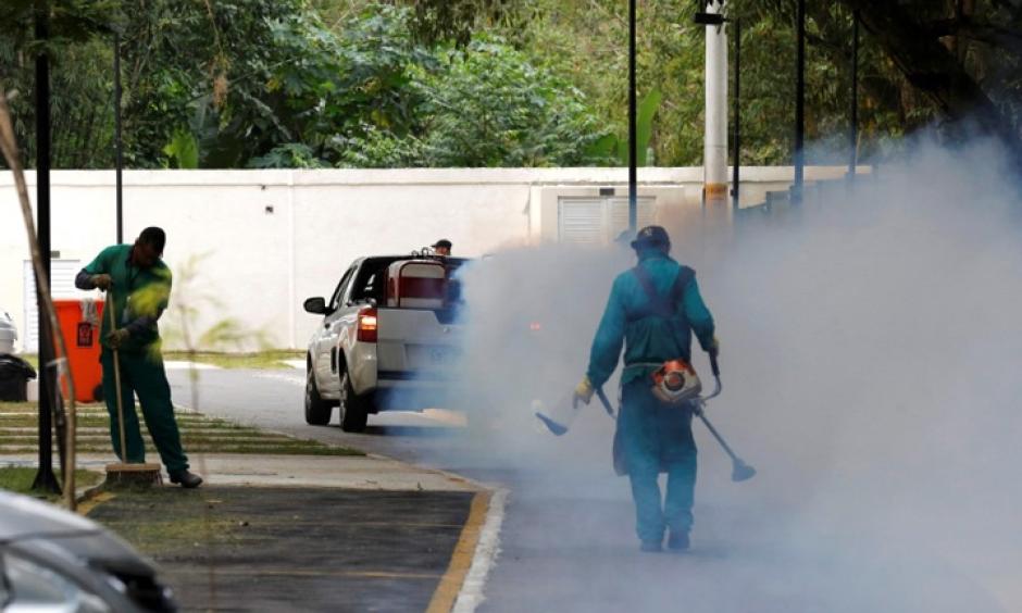 A truck sprays insecticide near grounds workers at Olympic media accommodations as part of preventative measures against the Zika virus and other mosquito-borne diseases in Rio de Janiero, Brazil. Photo: Chris Helgren, Reuters