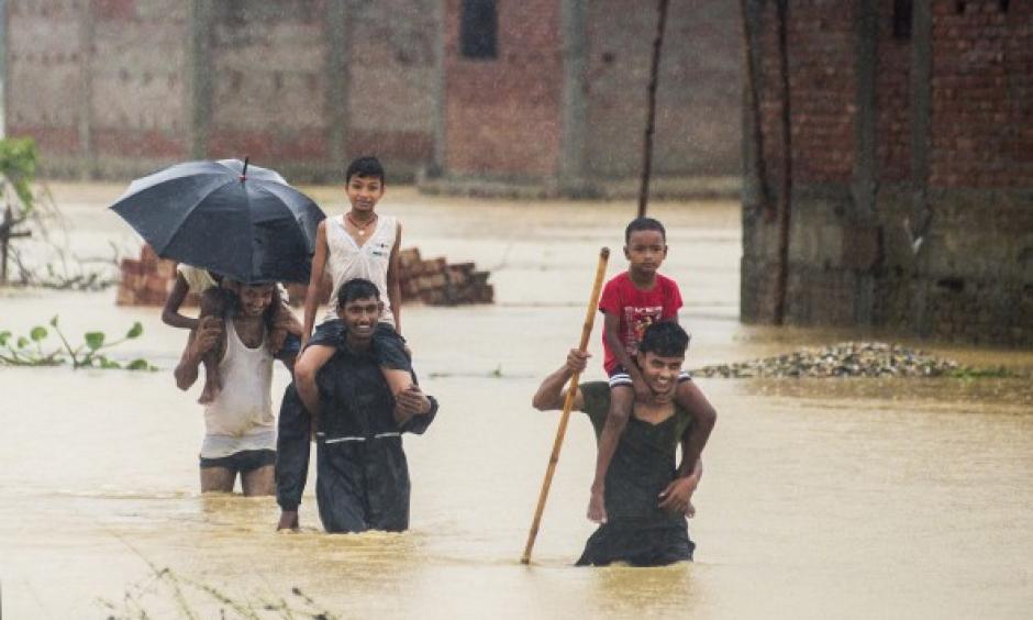 Nepalese men carry children on their shoulders as they wade through flood waters in village Ramgadhwa in Birgunj, Nepal, Sunday, Aug. 13, 2017. Photo: Manish Paudel, AP