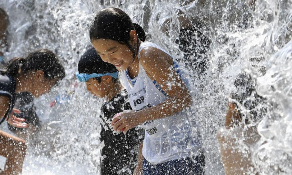 In this July 14, 2018 file photo, children play in a water fountain set up at a park in Tokyo during an extreme heat wave. (Kyodo)