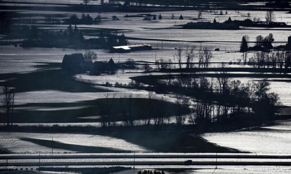 A police vehicle, bottom right, travels on the Trans-Canada Highway past flooded farmland in Abbotsford, British Columbia, on Wednesday, Nov. 17, 2021. (Darryl Dyck/The Canadian Press via AP)