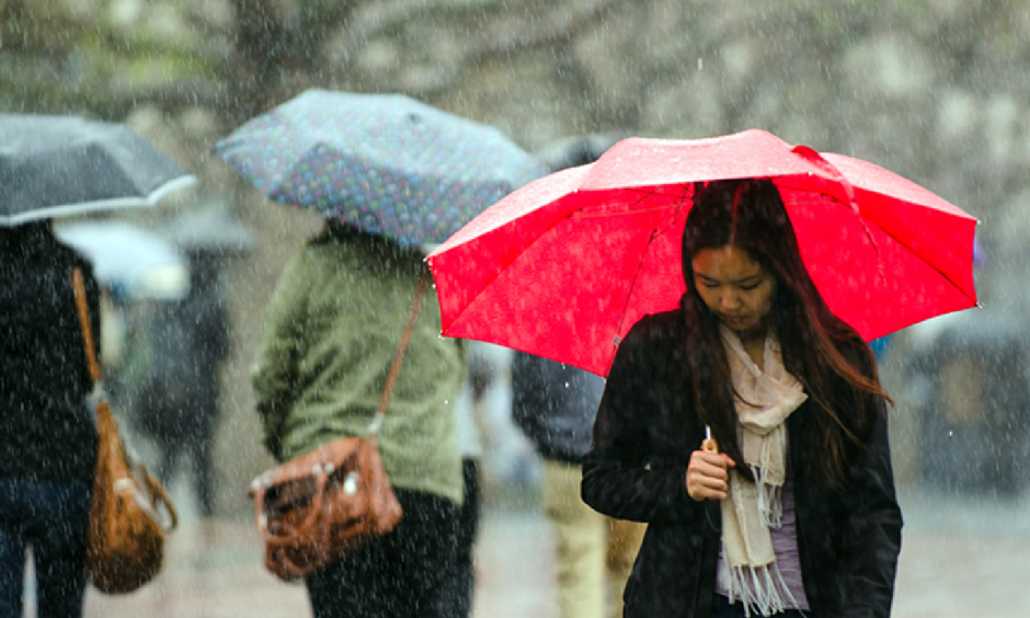 Passersby brave the heavy rains in California. Photo: Kevin Ho Nguyen