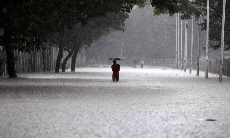 An Indian man shelters under an umbrella as he walks through floodwaters in Chennai on December 1, 2015, during a downpour of heavy rain in the southern Indian city. Photo by STRDEL/AFP/Getty Images