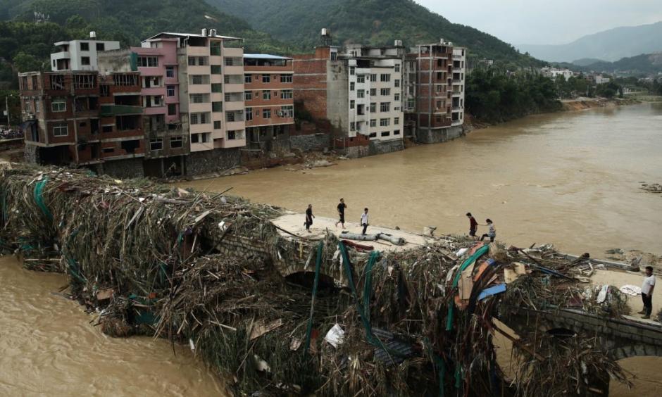 Residents gingerly walking over a bridge mounded with debris in Bandong Town in China’s Fujian province. Photo: STR / AFP / Getty Images