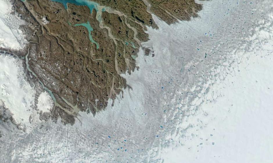 Numerous melt ponds are visible in this image of Greenland’s southwest coast, captured by NASA’s Aqua satellite on June 12, 2016. The grayish-blue band also is indicative of melting at the surface. Photo: NASA EOSDIS