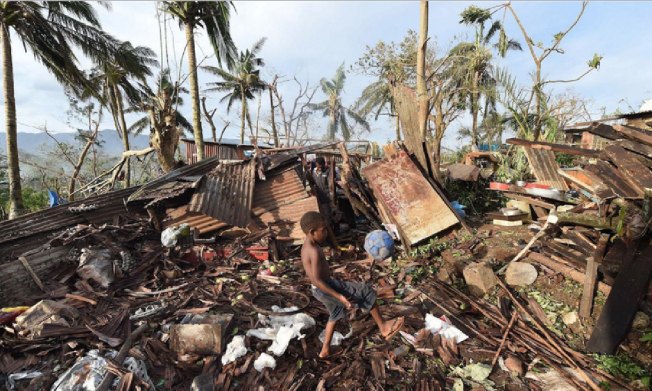 In Vanuatu's capital, Port Vila, a boy named Samuel kicked a ball through the ruins of his family's home as his father, Phillip, at back, picked through the debris on Monday. Image: Dave Hunt, AP