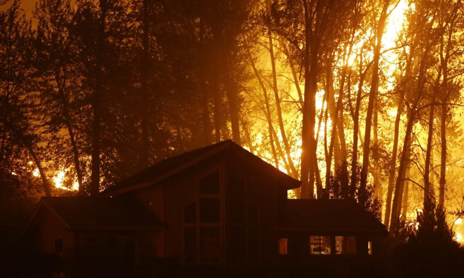 A wildfire burns behind a home in Twisp, Washington, in August. Authorities urged people in the town to evacuate because of the fast-moving blaze. (Ted S. Warren/AP)