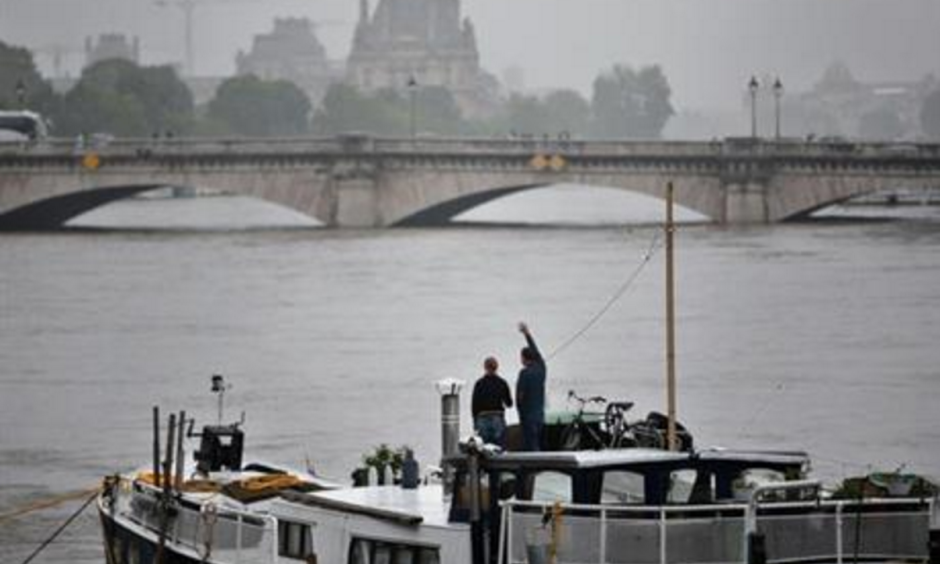 A man waves to somebody on a barge on the Seine river during floods, in Paris, Sunday, June 5, 2016. The riverside Grand Palais exhibition hall in Paris reopened Sunday as floodwaters slowly receded from the French capital, though risks remain for other regions. Photo: Thibault Camus, AP