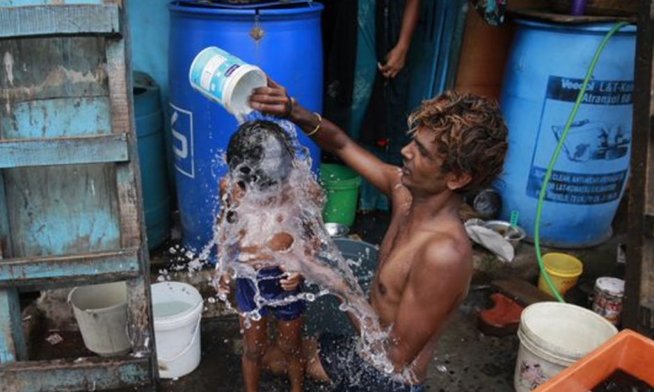 In this May 23, 2016 file photo, a man bathes his son on a hot afternoon in Mumbai, India. Federal scientists say Earth sizzled to its 13th straight month of record heat in May. Photo: Rafiq Maqbool, AP