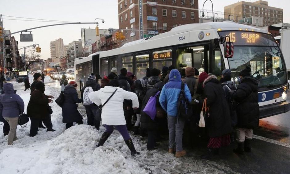 Commuters trudge through piles of snow boarding a bus in Manhattan. Photo: AP
