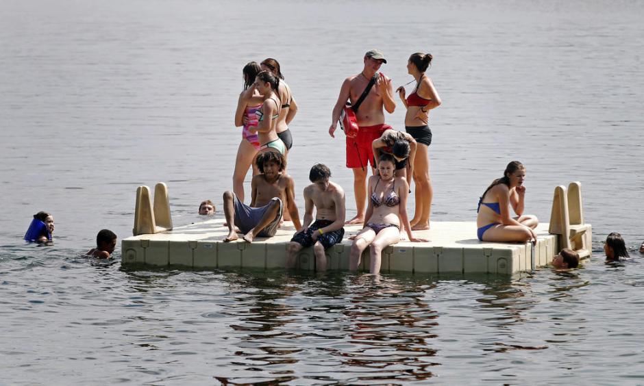 A lifeguard, center in red, overseas a platform as people beat the oppressive heat and humidity Thursday, July 21, 2016, at Lake Harriet in Minneapolis. Photo: Jim Mone, AP