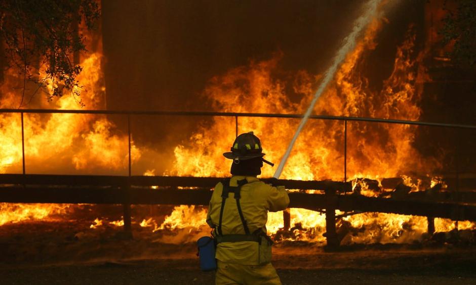 A firefighter sprays a hose into a Keysight Technologies building in Santa Rosa last month during the wildfires that killed 42 people and destroyed 8,700 homes and buildings. Photo: Jeff Chiu, Associated Press Photo
