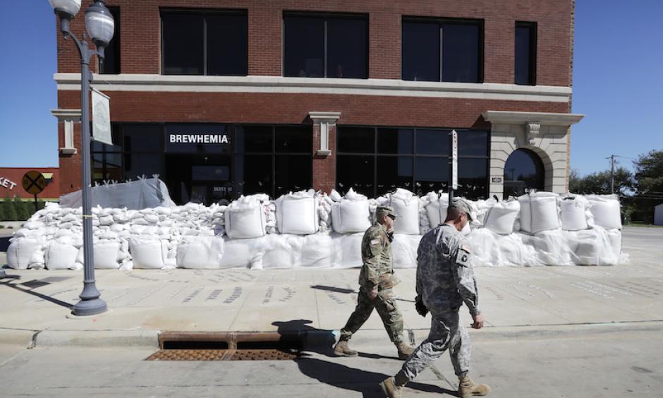 Iowa National Guard members walk past a local business covered in sandbags, Monday, Sept. 26, 2016, in Cedar Rapids, Iowa. Residents are waiting anxiously as a quickly rising Cedar River threatens to inundate their city with devastating floodwaters for the second time in eight years. Photo: Charlie Neibergall, AP
