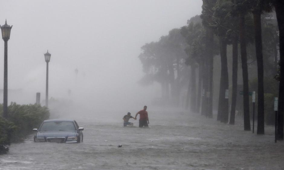 Pedestrians walk by a flooded car on a street as storm surge associated with Tropical Storm Irma hits Charleston, S.C., Monday, Sept. 11, 2017. Photo: Mic Smith, AP