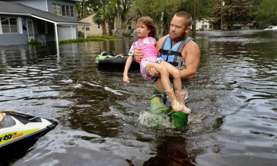 Tommy Nevitt carries Miranda Abbott, 6, through flooding caused by Hurricane Irma on the west side of Jacksonville, Monday, Sept. 11 2017. Photo: Dede Smith, The Florida Times-Union via AP