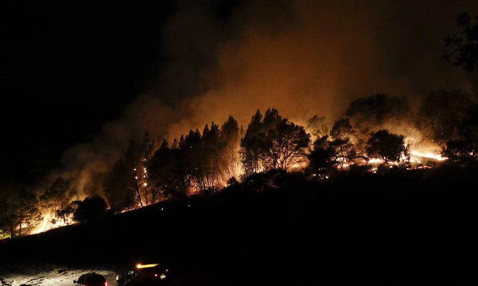 Firefighters watch from their fire trucks as wildfires continue to burn on Thursday, near Calistoga, Calif. Jae C. Hong/AP